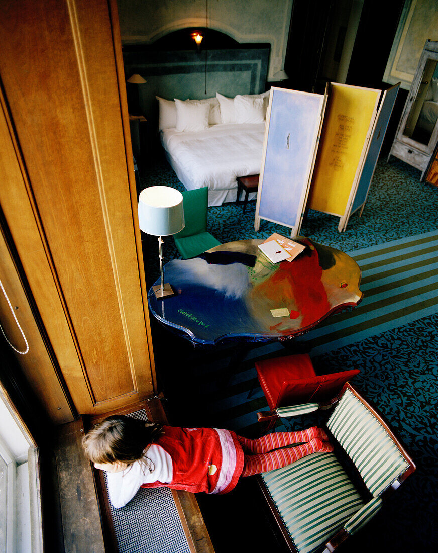 Mädchen blickt aus dem Fenster im Directors Room 207, Hotel New York, Kop van Zuid, Rotterdam, Niederlande