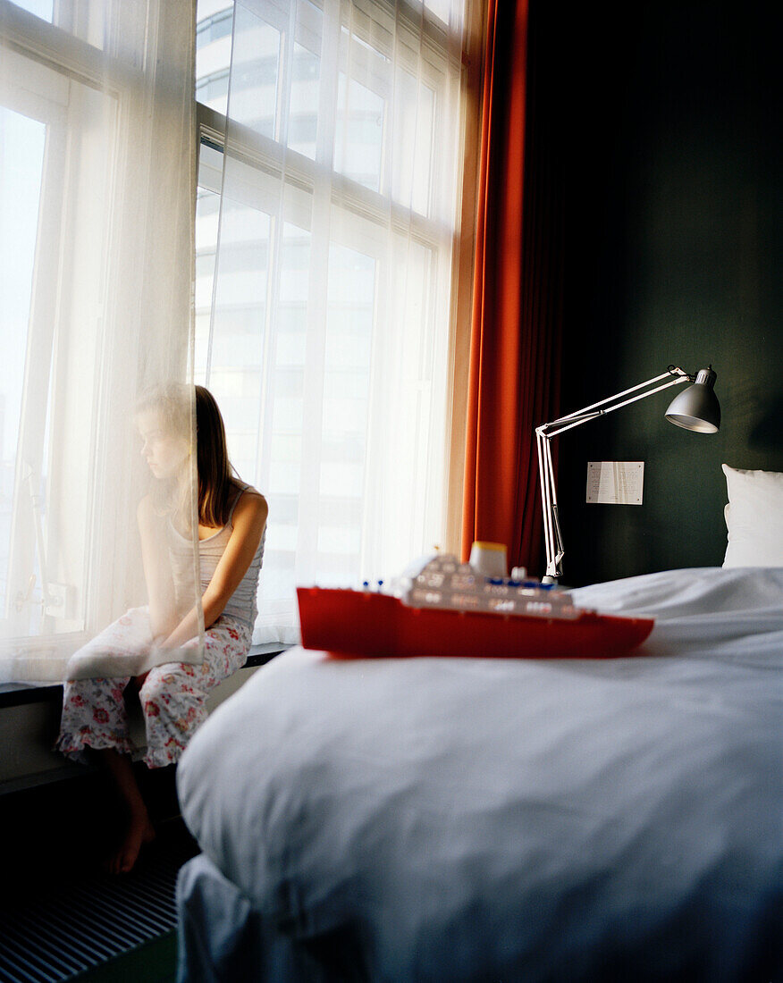 Girl looking out of a hotel window, Rotterdam, Netherlands