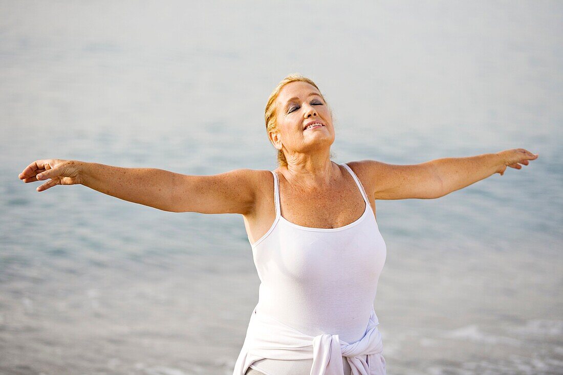 Portrait of a senior adult woman stretching at the beach