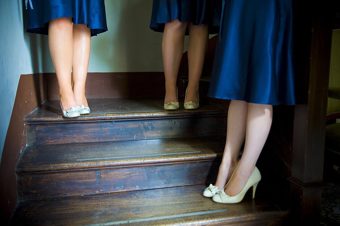 Cropped view of bridesmaids in blue satin dresses standing on stairwell