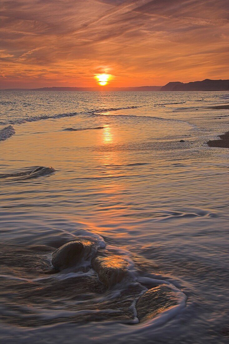 Sunset on the beach at Burton Bradstock looking towards Lyme Regis in the Distance Dorset
