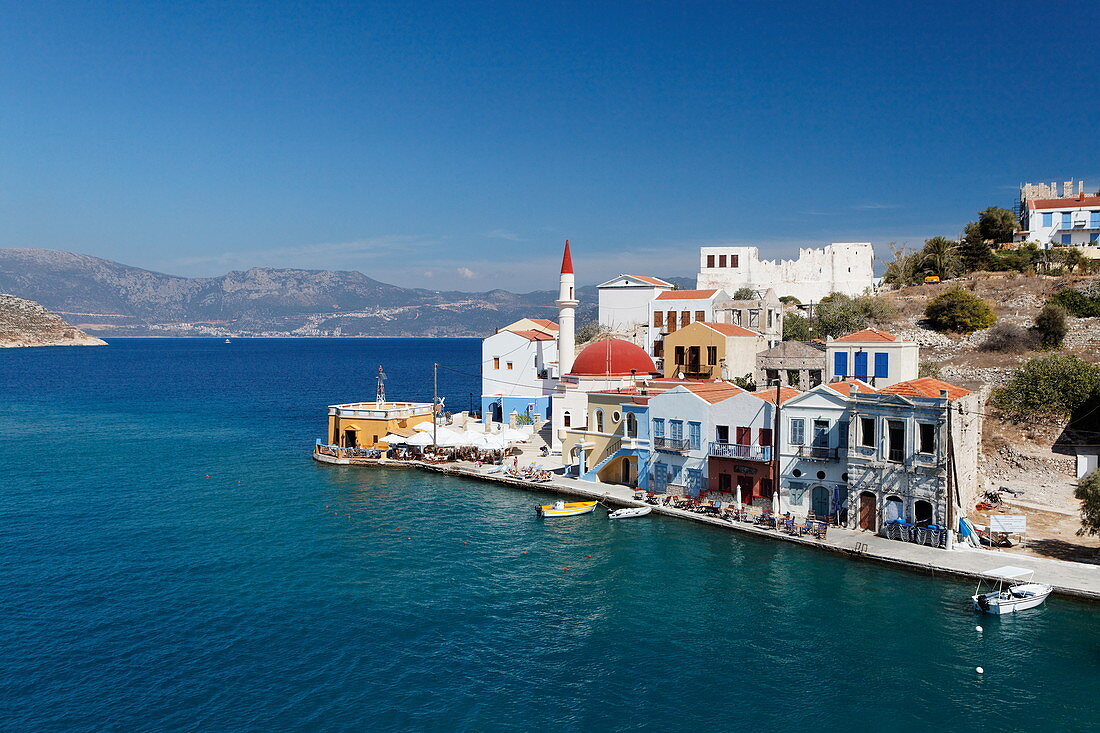 Blick auf Häuser an der Küste im Sonnenlicht, Kastelorizo Megisti, Dodekanes, Griechenland, Europa