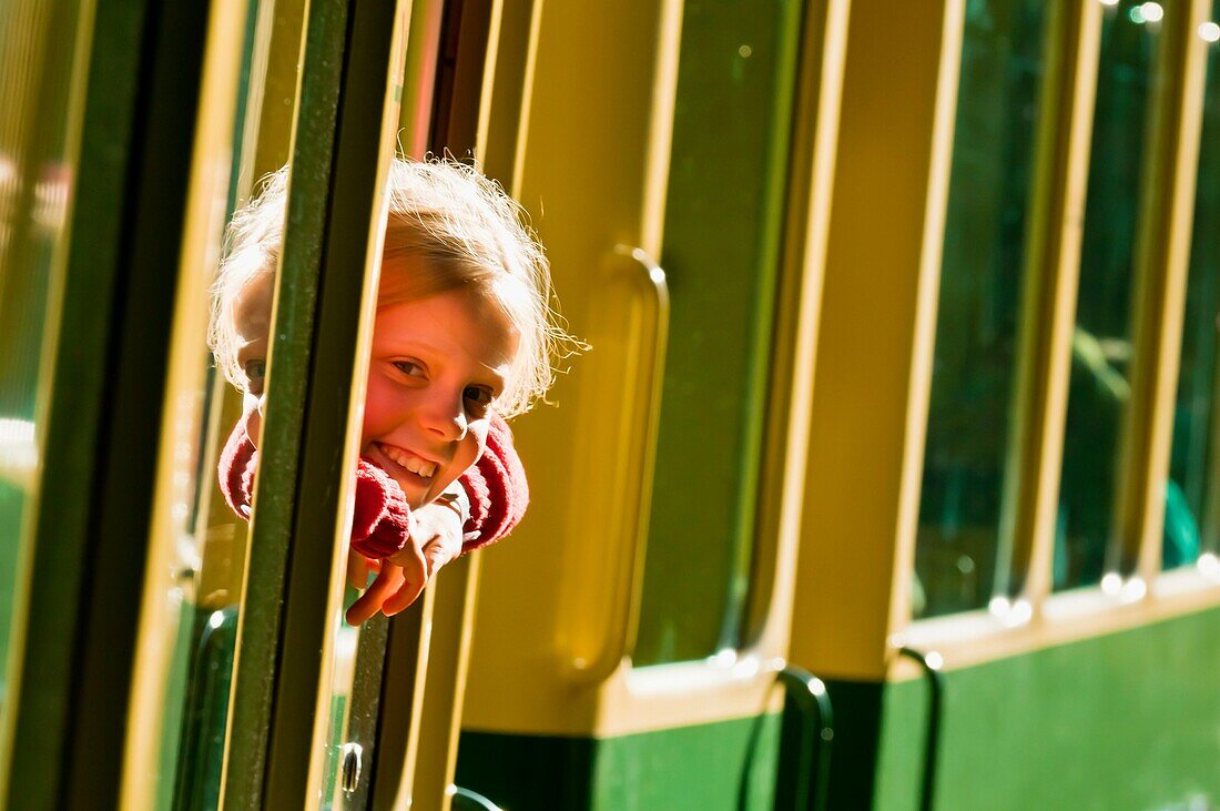 Young Swiss girl looking out of train window, Jungfrau Railway train descending from Wengernalp to Wengen, Swiss Alps, Canton Bern, Switzerland