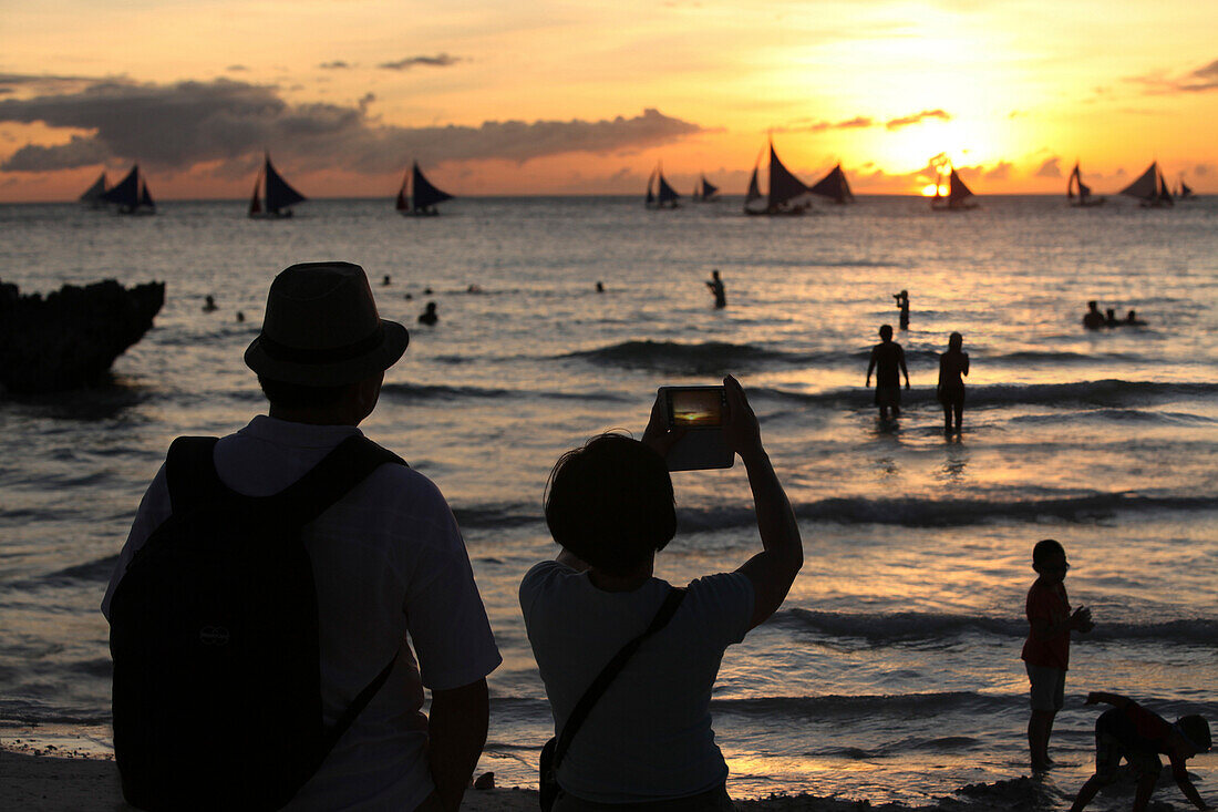 Zwei Touristen machen Fotos im Sonnenuntergang, Boracay, Insel Panay, Visayas, Philippinen