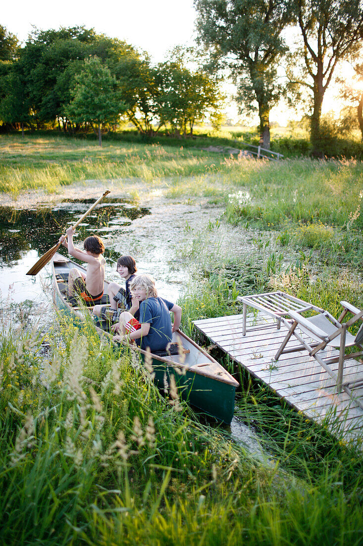 Drei Jungen in einem Kanu auf einem Teich, Haus Strauss, Bauernkate in Klein Thurow, Roggendorf, Mecklenburg-Vorpommern, Deutschland