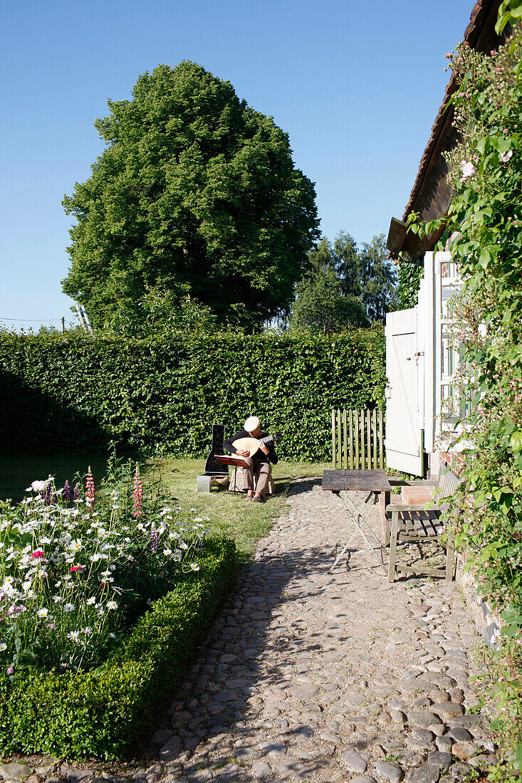 Mann musiziert im Garten, Haus Strauss, Bauernkate in Klein Thurow, Roggendorf, Mecklenburg-Vorpommern, Deutschland