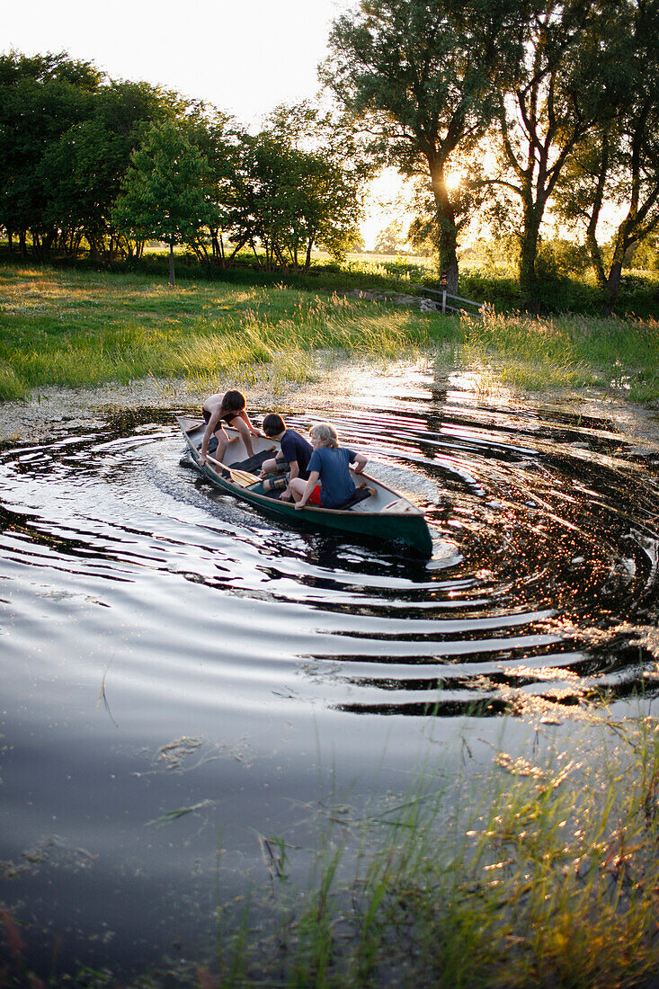 Drei Jungen in einem Kanu auf einem Teich, Haus Strauss, Bauernkate in Klein Thurow, Roggendorf, Mecklenburg-Vorpommern, Deutschland