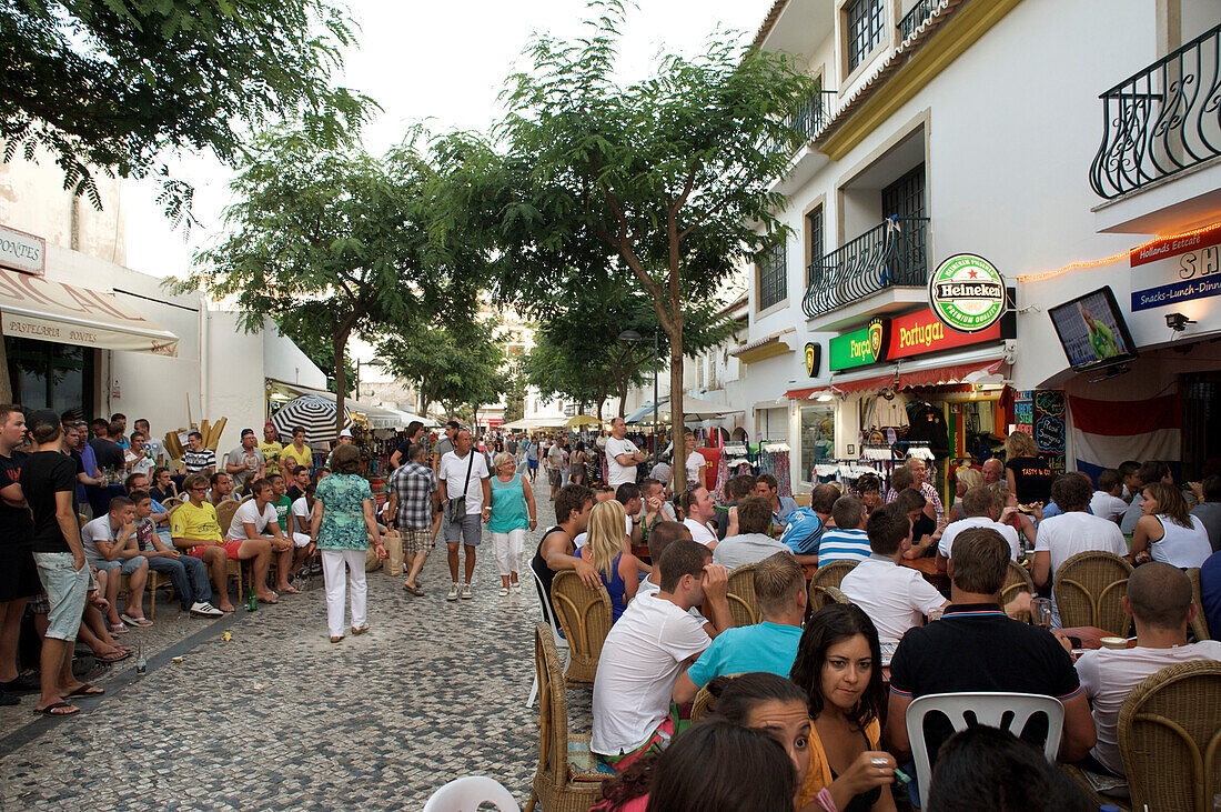 Viele Menschen auf der Straße und in Restaurants am Abend, Albufeira, Algarve, Portugal, Europa
