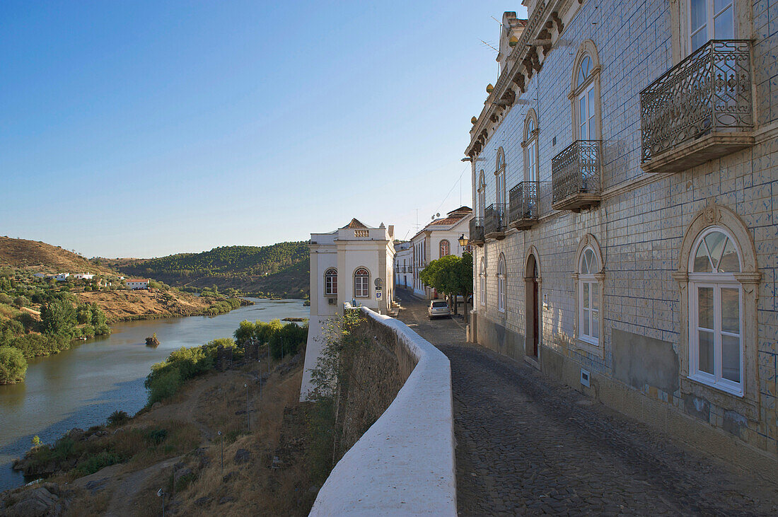 Street and houses above Rio Guadiana river at Mertola, Alentejo, north of the Algarve, Portugal, Europe