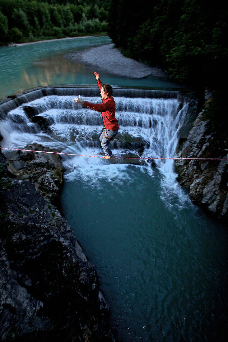 Young man balancing on a highline over a stream, Fuessen, Bavaria, Germany, Europe