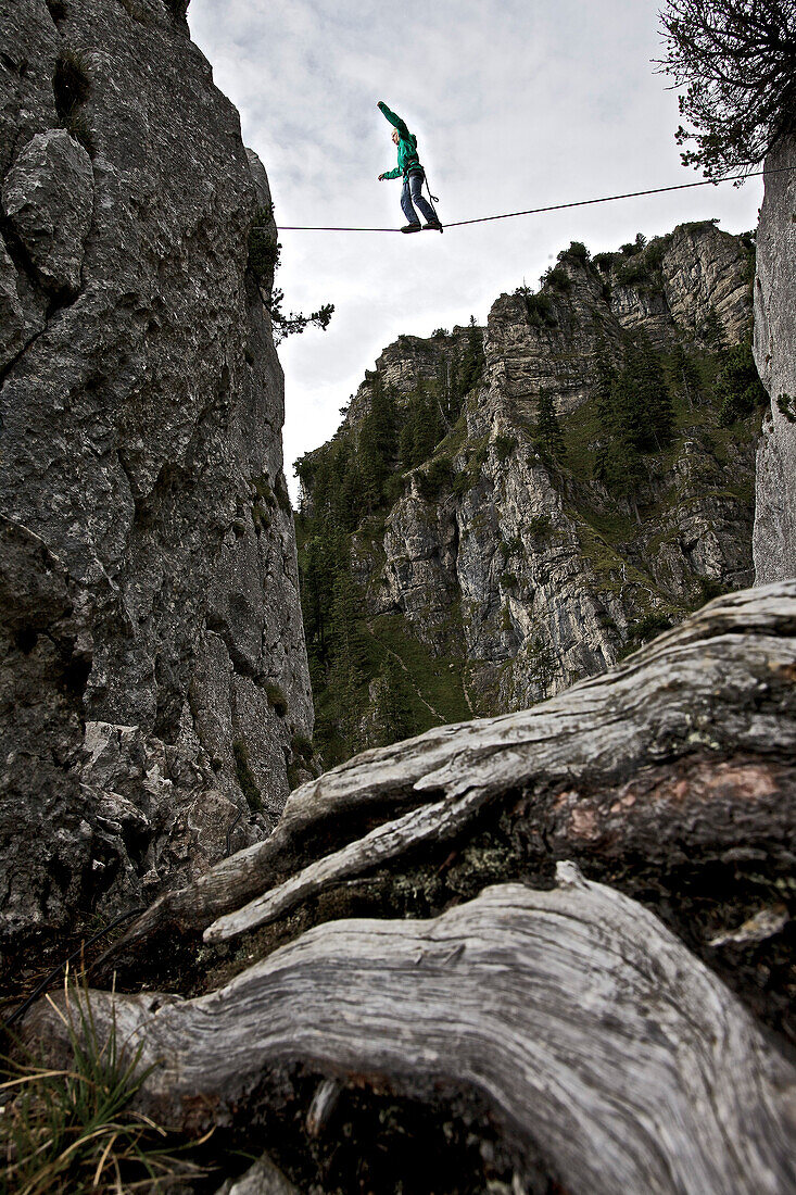 Young man balancing on a highline between two rocks, Oberammergau, Bavaria, Germany, Europe