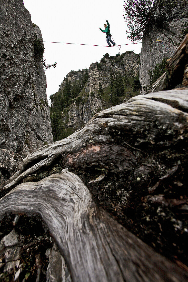 Junger Mann balanciert über eine Highline zwischen zwei Felsen, Oberammergau, Bayern, Deutschland, Europa