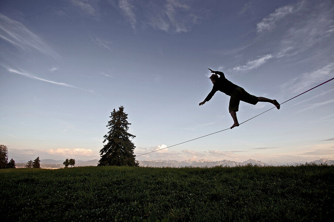 Young man balancing on a longline at dusk, Auerberg, Bavaria, Germany, Europe