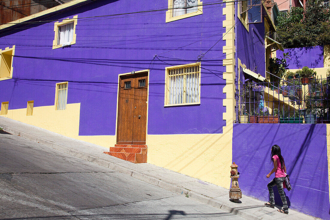 Girl walks up steep street past purple building, Valparaiso, Valparaiso, Chile, South America