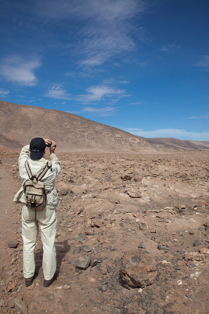 Besucher fotografiert Geoglyphen mit Motiven von Tieren und Menschen am Monumento National Geoglifos de Pintados in der Atacama Wüste, nahe Iquique, Tarapaca, Chile, Südamerika