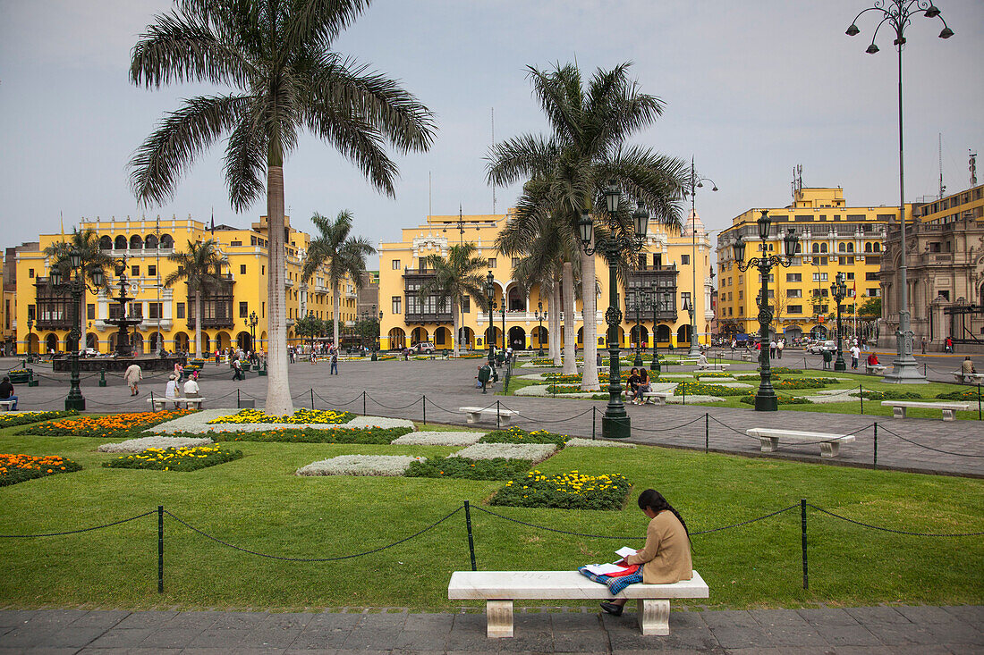 Woman sits on park bench at Plaza de Armas square, Lima, Peru, South America