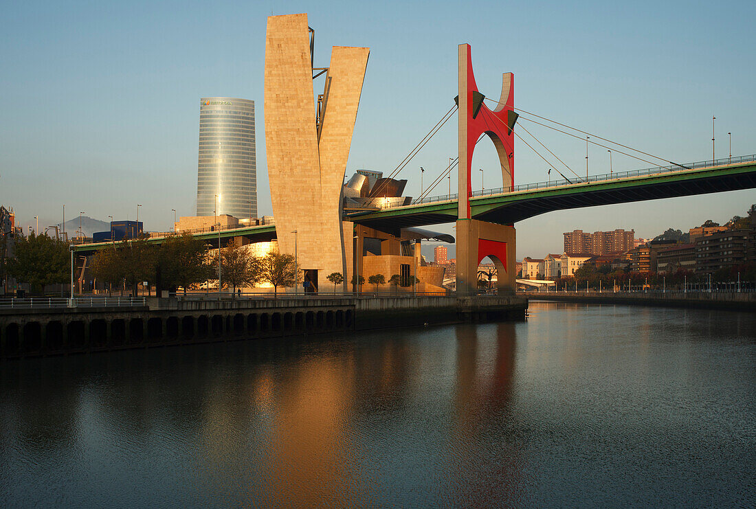 Das Hochhaus Torre Iberdrola und Guggenheim Museum Moderner und Zeigenössischer Kunst mit der Brücke Puente de la Salve im Abendlicht, Rio Nervion, Bilbao, Provinz Bizkaia, Baskenland, Euskadi, Nordspanien, Spanien, Europa