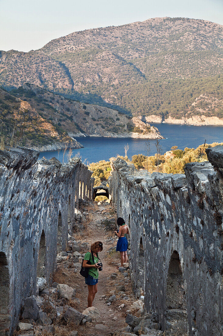 Frauen fotografieren im Galeriegang auf der Insel Gemiler im Golf von Fethiye, lykische Küste, Mittelmeer, Türkei