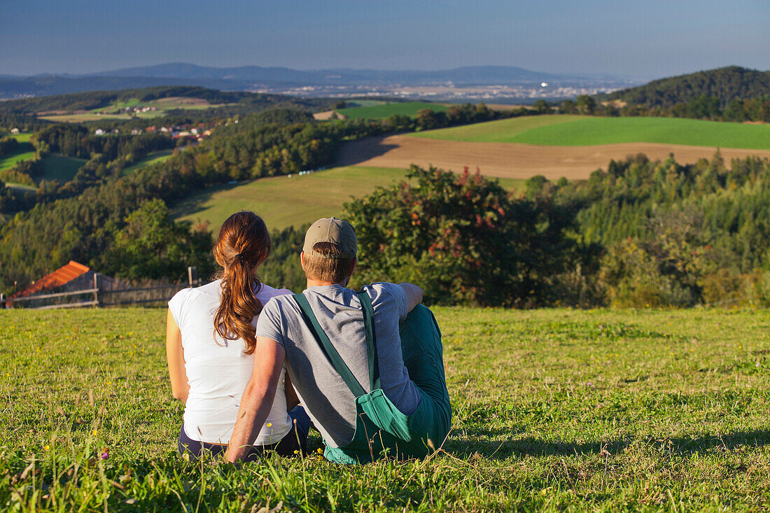 Young farmer couple sat in the middle of a meadow, Farm, Lower Austria, Austria
