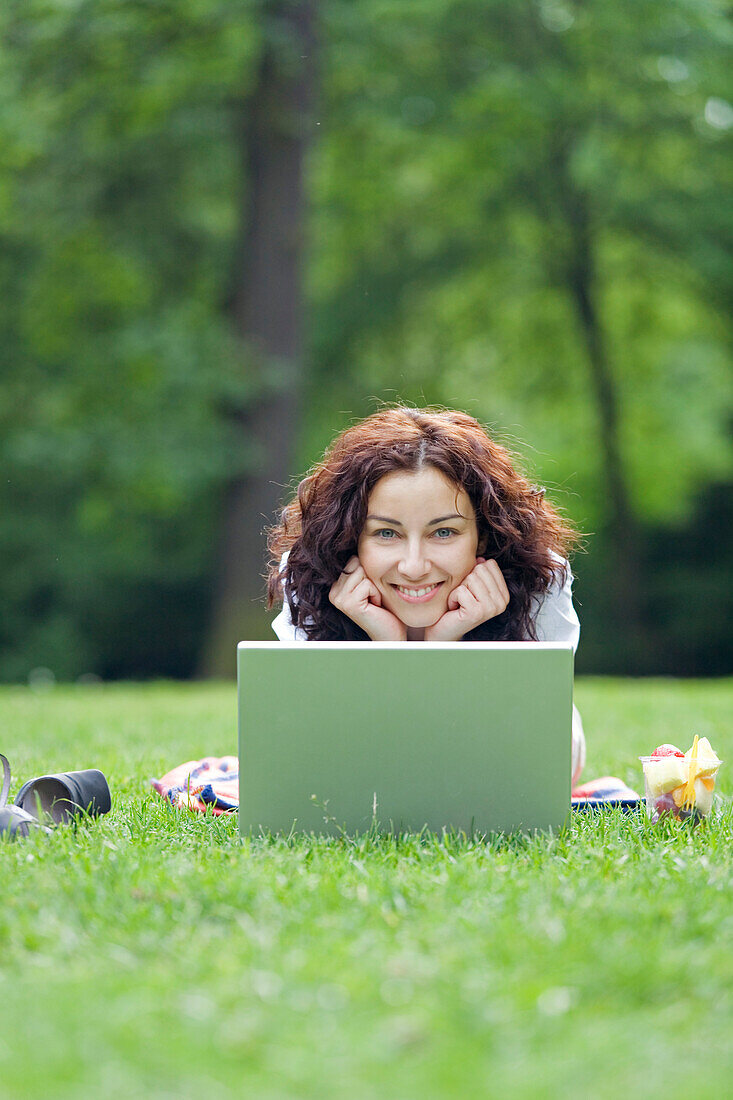Businesswoman with laptop relaxing in park at lunch-time