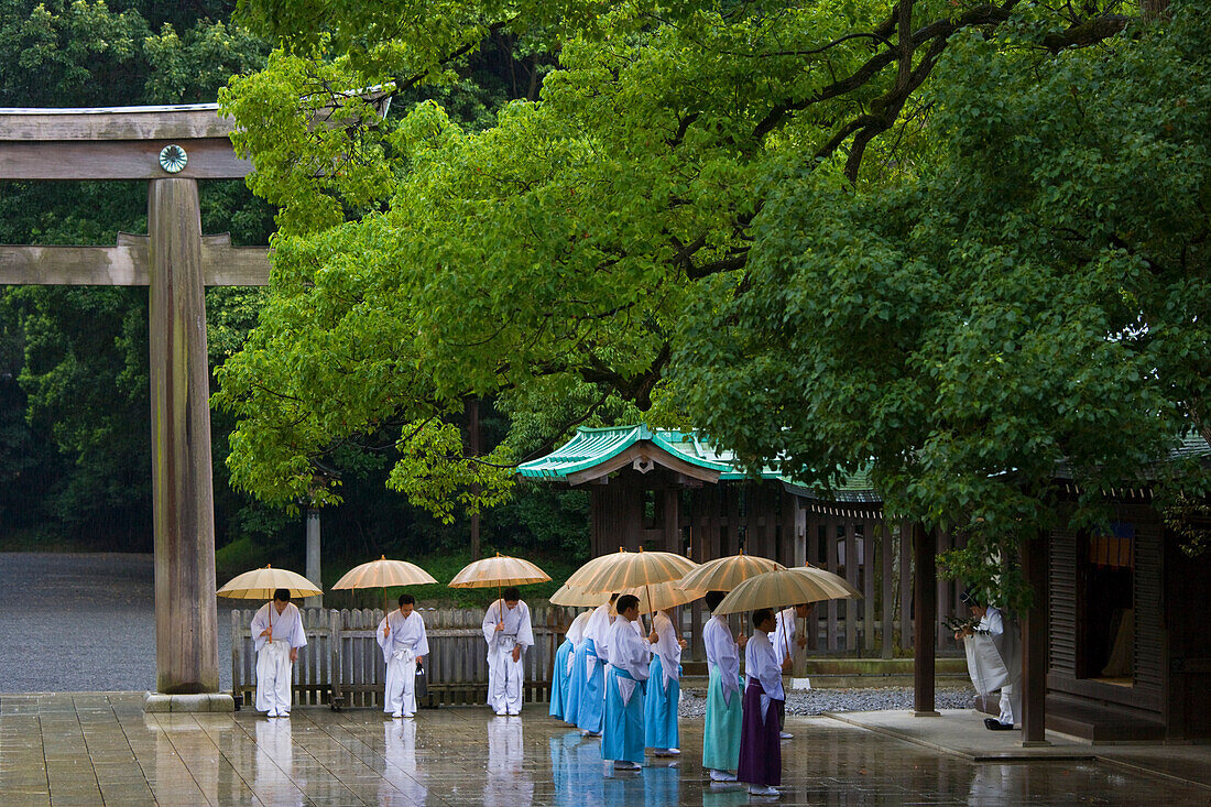 Rain accentuates the somber mood of the central sanctuary where Kannushi Shinto priests all carry umbrellas at Meiji-Jingu Shrine, located in the Shibuya district of Tokyo, Japan.