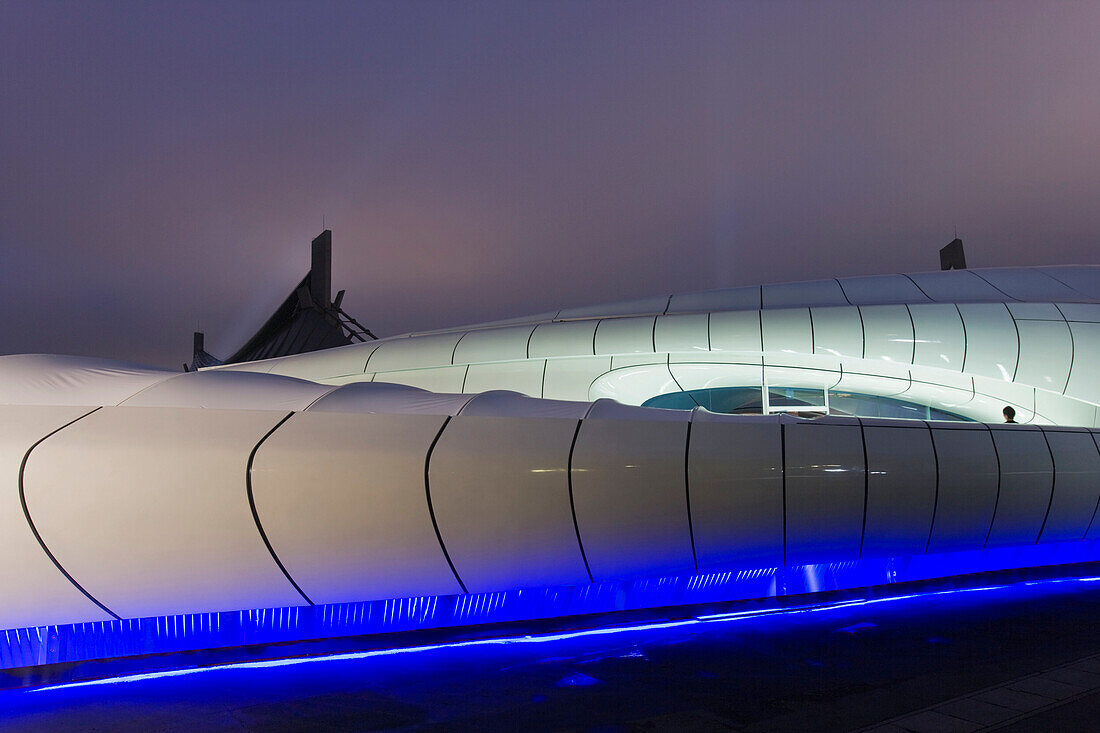 The traveling art museum, Chanel Mobile Art, designed by architect Zaha Hadid, seems perfectly situated in its temporary Tokyo location next to the still-futuristic National Yoyogi Stadium at twilight in Olympic Plaza, located in the trendy Harajuku distr