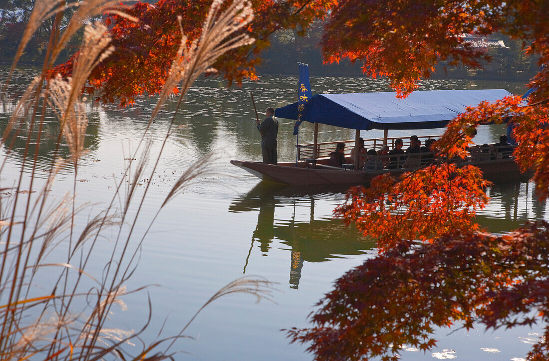 An excursion boat is poled around Osawa Pond, once part of Saga Imperial Villa, at Daikakuji Temple, located in the northwestern area of Kyoto, Japan.