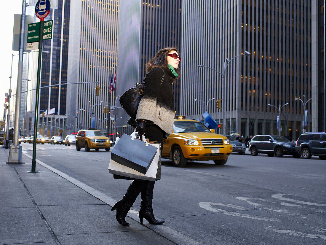 Elegant woman in New York street. Woman in New York street. She is holding shopping bags, looking across road.