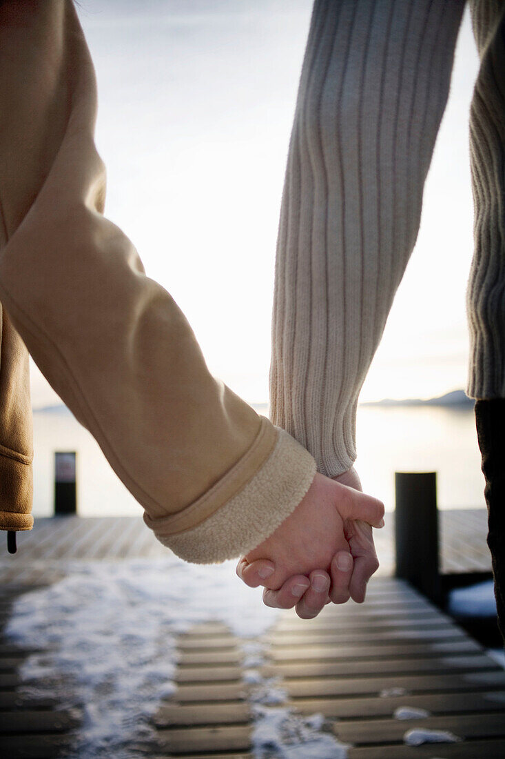 Hands holding on snowy pier