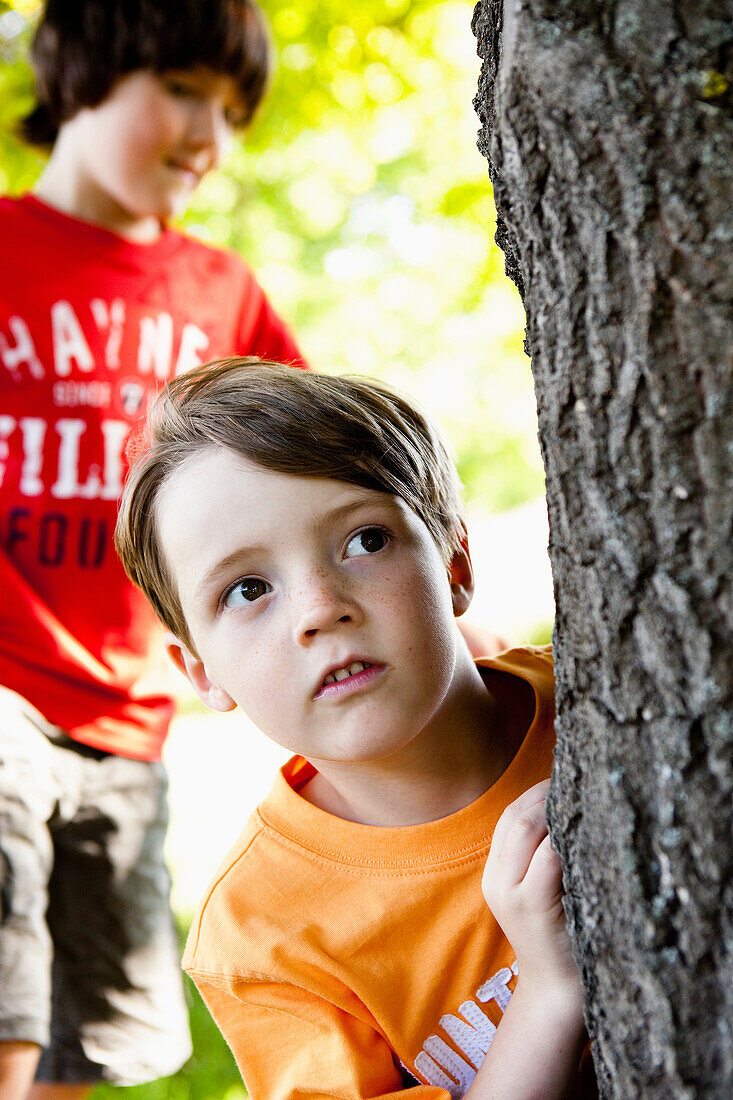 Two Boys Hiding Behind Tree