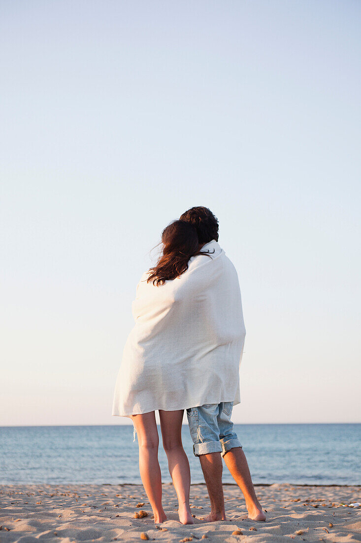 couple cuddled up in beach towel