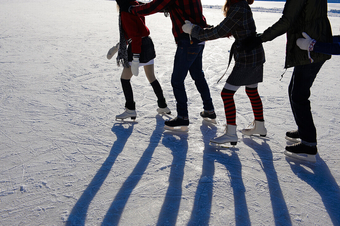 Teenagers ice_skating. Four teenagers ice_skating in a conga line outdoors