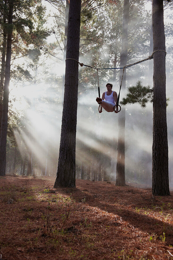 Gymnast using rings in forest. Gymnast using rings in forest