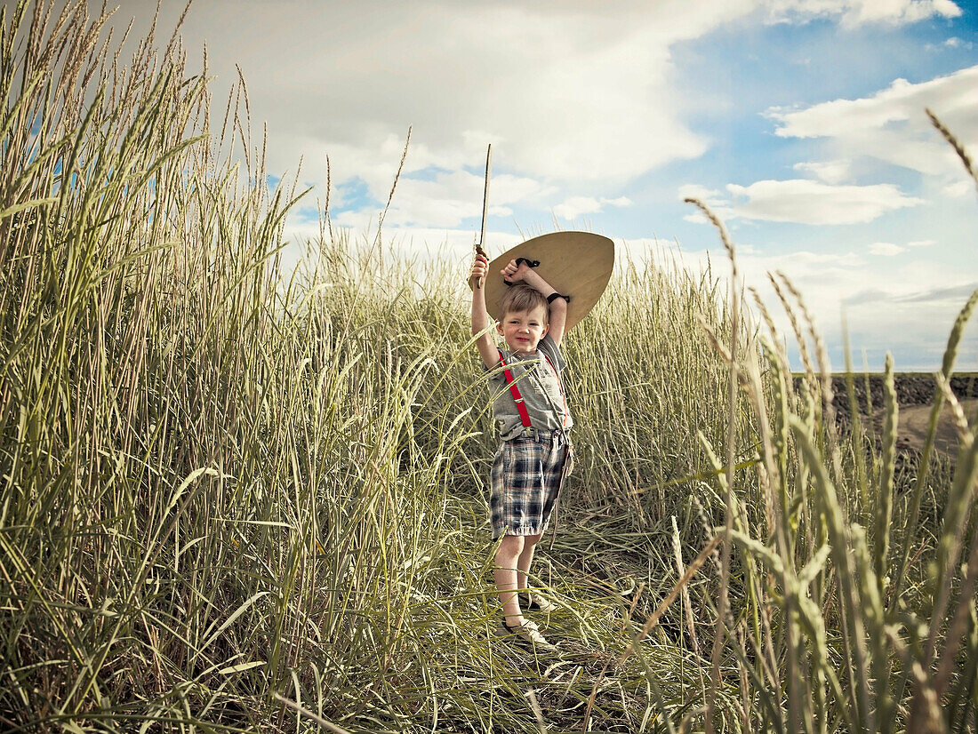 Boy playing with sword in wheat field. Boy playing with sword in wheat field