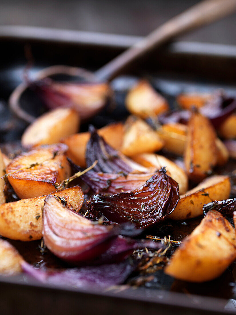 Close up of roasted vegetables in tray. Balsamic Roast Potatoes withRed Onions & Rosemary