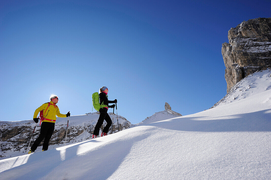 Junge Frau und junger Mann steigen auf Skitour zum Corno d'Angolo auf, Felsturm im Hintergrund, Corno d'Angolo, Cortina, Venetien, Dolomiten, Italien, Europa