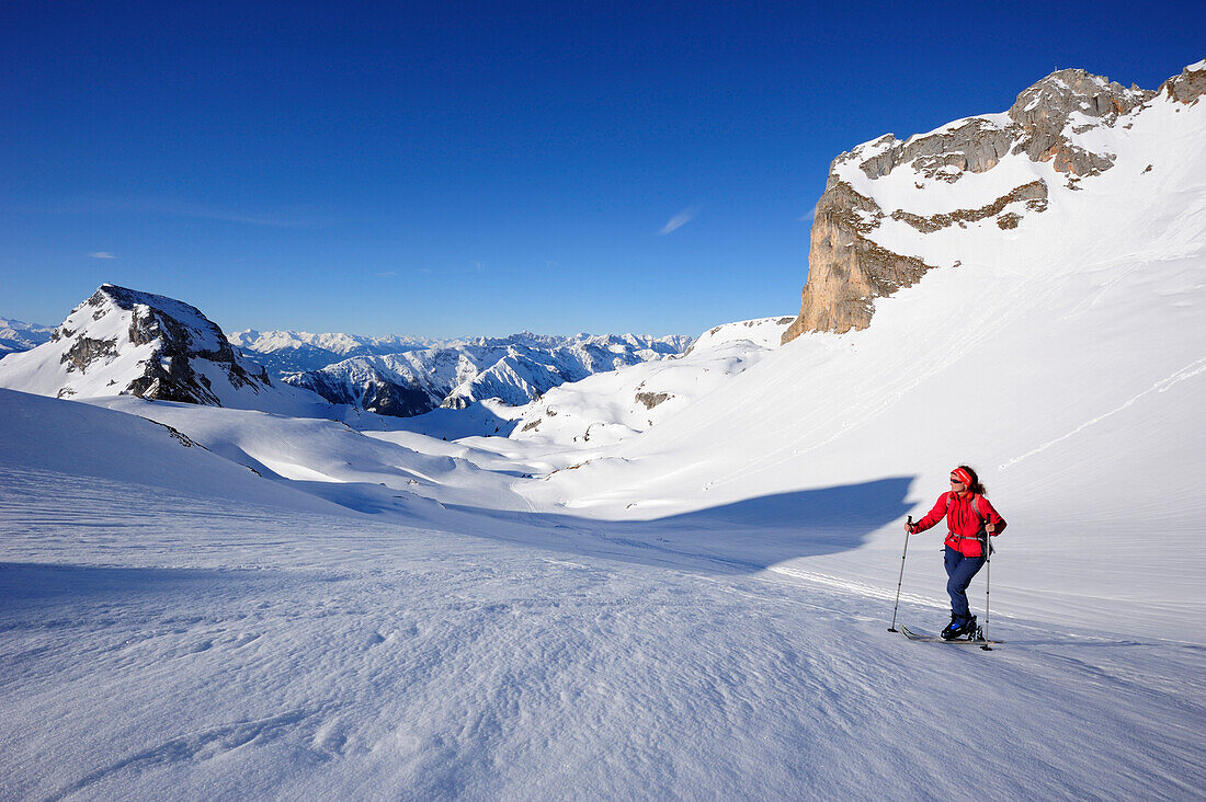 Woman with crosscountry skis ascending to Rofanspitze, Karwendel range in the background, Rofanspitze, Rofan, Tyrol, Austria, Europe