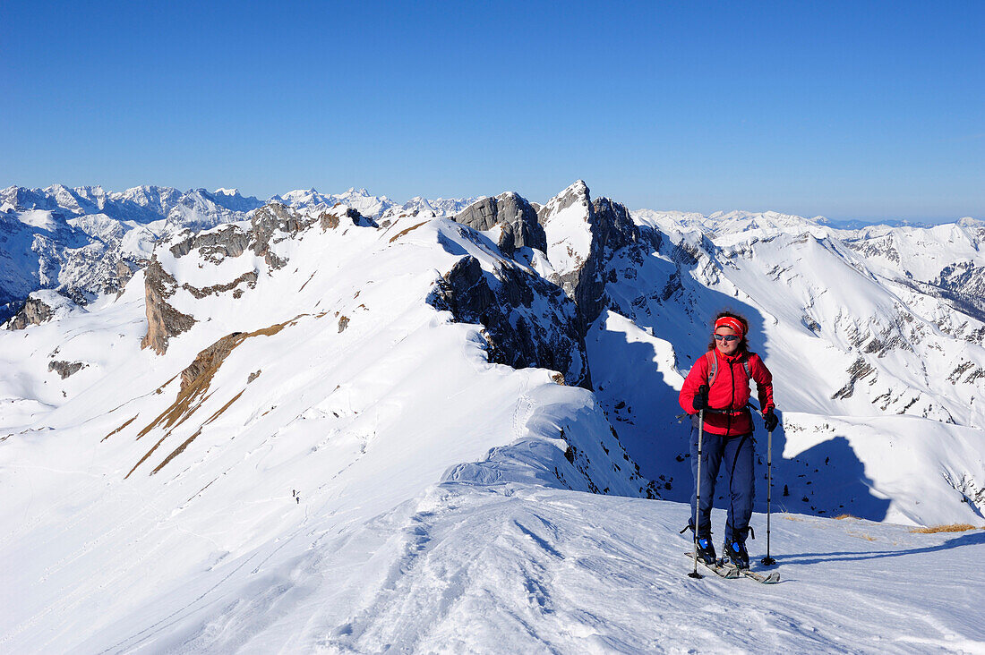Woman with crosscountry skis ascending to Rofanspitze, Seekarlspitze, Hochiss and Karwendel range in the background, Rofanspitze, Rofan, Tyrol, Austria, Europe