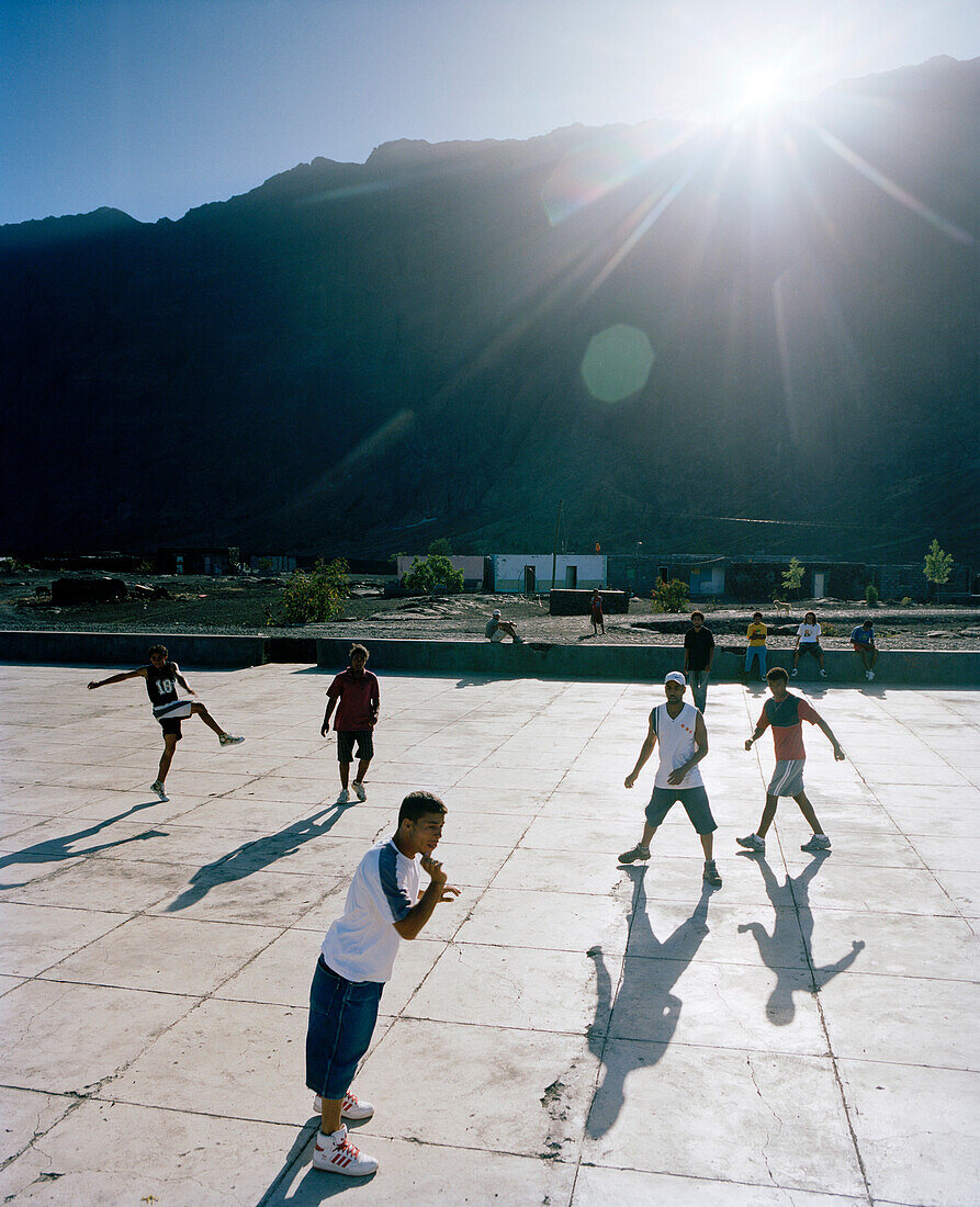 Jungen spielen Fußball im Sonnenlicht in Portela, letzte Sonne über dem Kraterrand, Cha das Caldeiras, Insel Fogo, Ilhas do Sotavento, Republic Kap Verde, Afrika