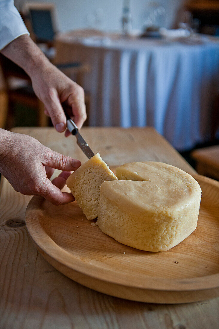Ein Mann schneidet frischer Käse mit Messer, Bayern, Deutschland