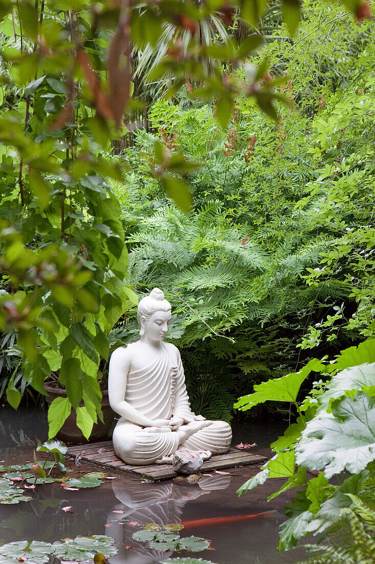 Buddha in einem Teich mit Seerosen und Kois im Garten von Andre Heller, Giardino Botanico, Gardone Riviera, Gardasee, Lombardei, Italien, Europa
