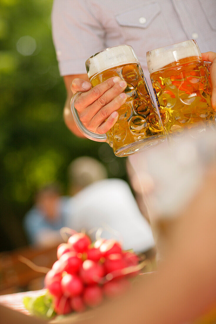 Menschen mit Bierkrügen und Radieschen in einem Biergarten, München, Bayern, Deutschland, Europa