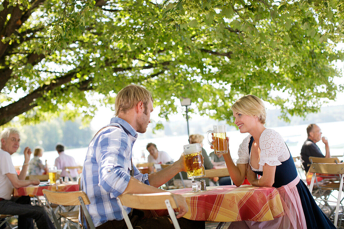 Menschen trinken Bier in einem Biergarten am Wörthsee, Bayern, Deutschland, Europa