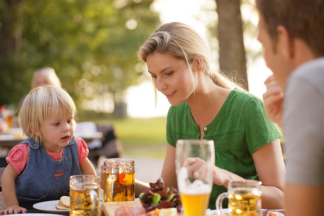 Familie mit Kind sitzt an einem Tisch im Biergarten, Starnberger See, Oberbayern, Bayern, Deutschland, Europa