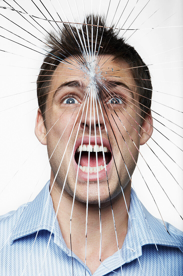 Young man behind cracked glass. Young man behind cracked glass shouting