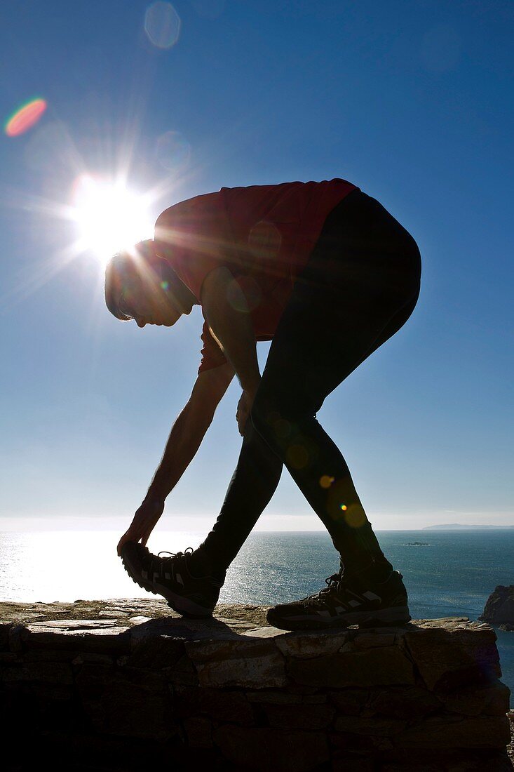 Man performing stretching exercise by the sea