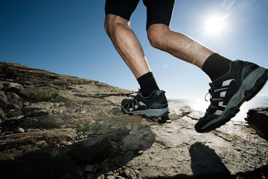 Man running along a rocky coastal path