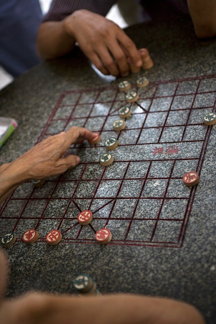 CHINA HONG KONG KOWLOON YAU MA TEI SHANGHAI AND MARKET STREET Image of cropped arms playing Chinese chess on a marbled chess table at an open space outside Tin Hau temple