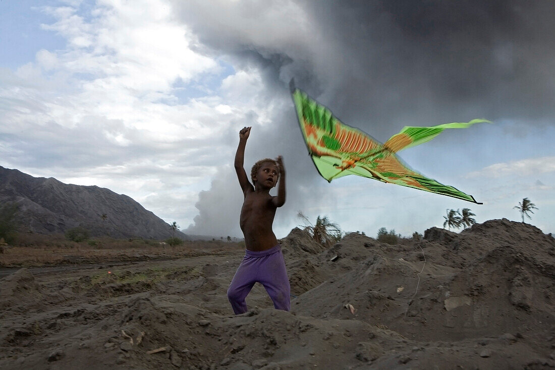 Kinder mit bunten Drachen im Vulkanasche, Tavurvur Vulkan, Rabaul, Ost-Neubritannien, Papua Neuguinea, Pazifik