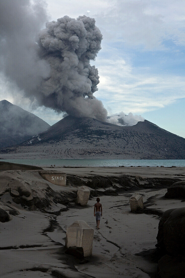 Children playing in the ruins of an old cement factory with the erupting Volcano in the background, Tavurvur Volcano, Rabaul, East New Britain, Papua New Guinea, Pacific